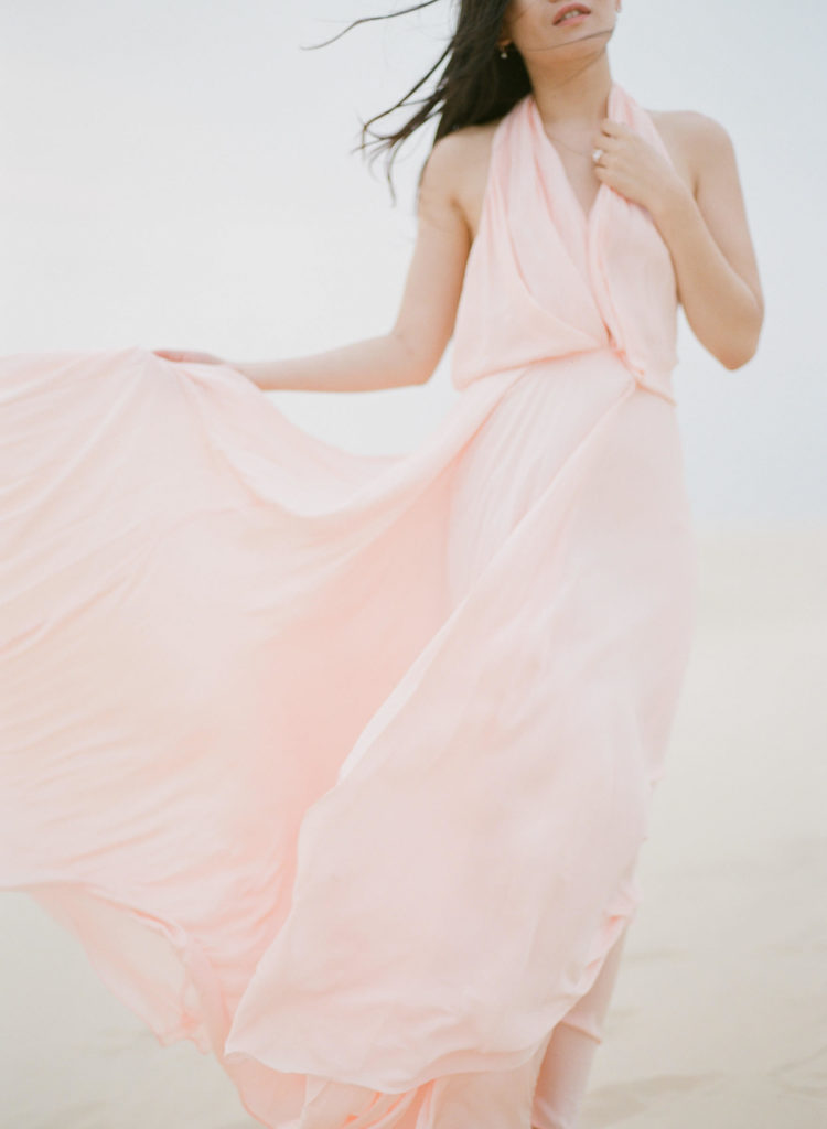 beautiful woman in pink flowy gown in sand dunes