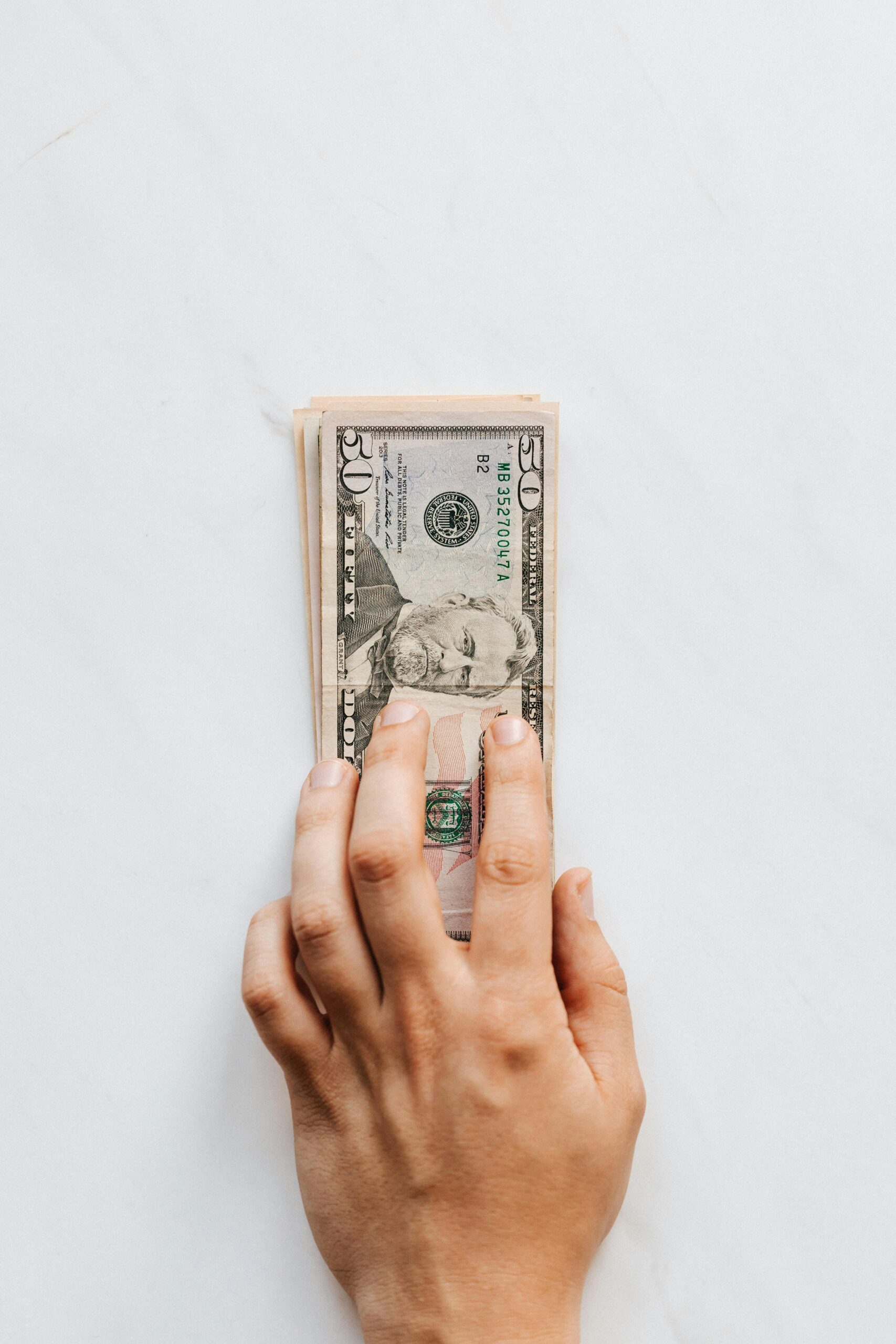 Photo of a hand holding dollar bills