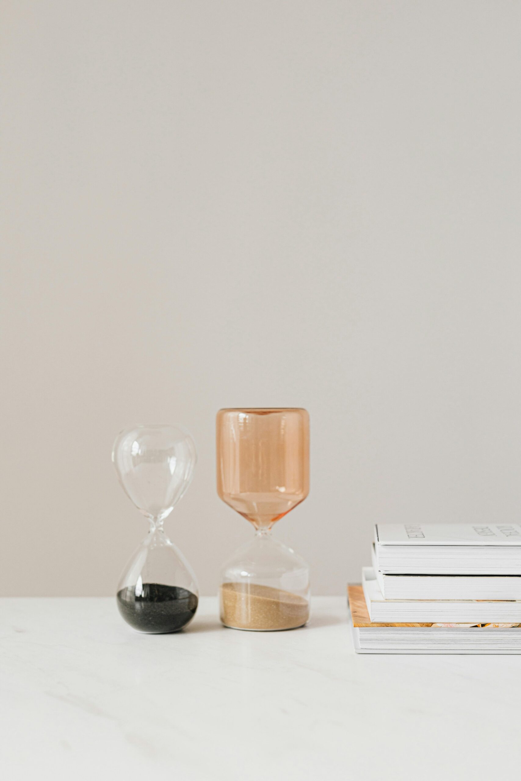 Photo of two hourglasses next to a stack of magazines